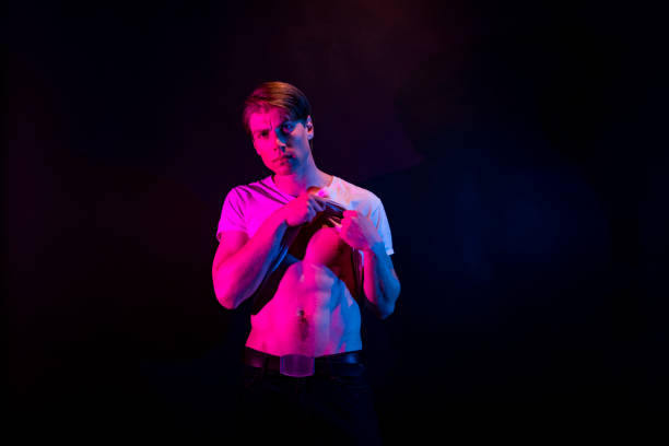 istock Sexy man in mood lighting undressing 1148021801