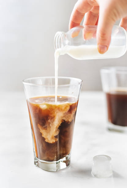 istock Iced coffee with pouring milk in glass on white background 1148029485
