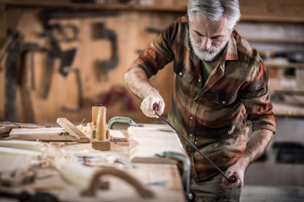 istock Expert carpenter using a drawknife on a wooden plank 1148031886