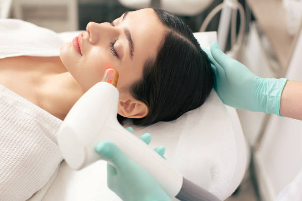 Close up of red laser on the face of woman Young woman lying with closed eyes while hand of professional medical worker conducting the procedure of laser scar removal on her face easy test stock pictures, royalty-free photos & images