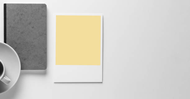 istock gray leather Notebook/book on white background isolated from above with a coffee cup and a empty yellow polaroid picture with space for text, mokup for business. 1148037249