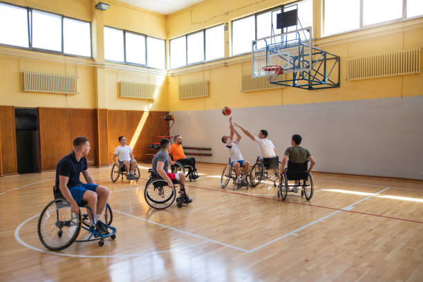 atleta adattivo su una sedia a rotelle che spara su un campo da basket - basket su sedia a rotelle foto e immagini stock