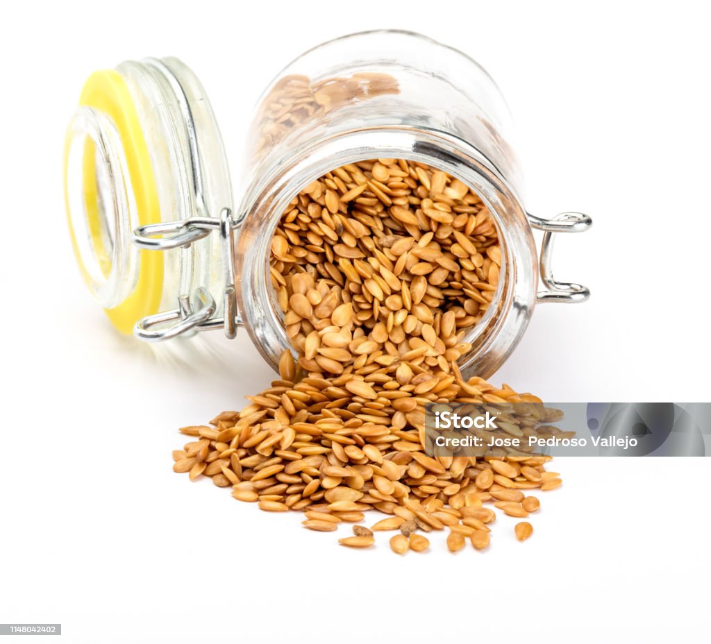 Golden flax seeds. Micronutrient beneficial for the organism that prevents and cures ailments. Rich in fiber and nutrients (manganese, vitamin B1, and above all, in omega-3 fatty acids) beneficial for healt (skin, weight loss, cholesterol reduction, celia Golden flax seeds. Micronutrient beneficial for the organism that prevents and cures ailments. In glass jar on white background. Rich in fiber and nutrients (manganese, vitamin B1, and above all, in omega-3 fatty acids) beneficial for healt (skin, weight loss, cholesterol reduction, celiac, antioxidants,"u2026) Cut Out Stock Photo