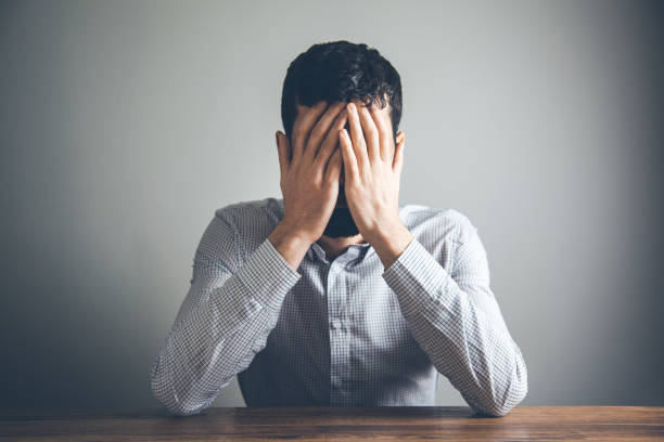 istock sad man hand in face on desk 1148043617
