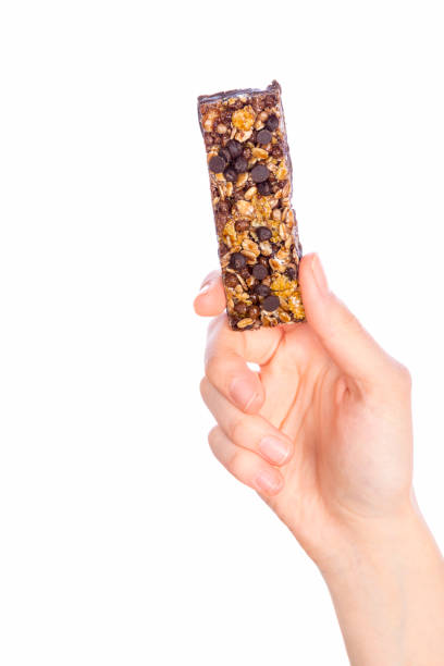 istock Woman holding grain cereal bar on white background 1148047495