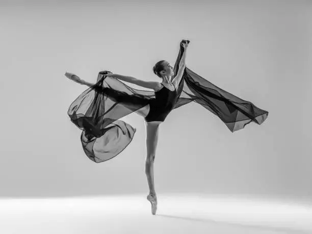 Young beautiful dancer dancing on gray background