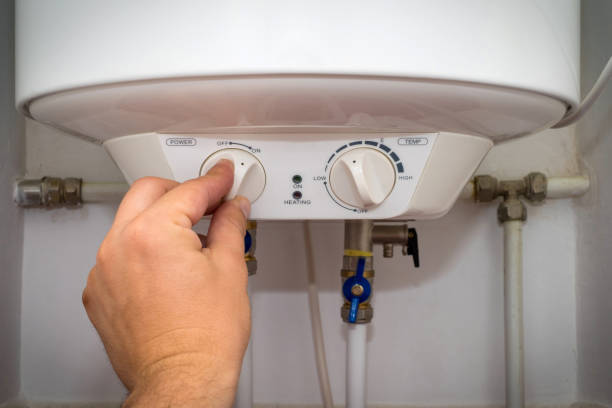 istock Man turns on the switch on control panel of home electric water heater (boiler). 1148057440