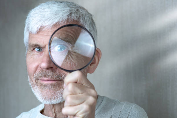 istock a gray-haired man in light clothes looking through a magnifying glass 1148064475