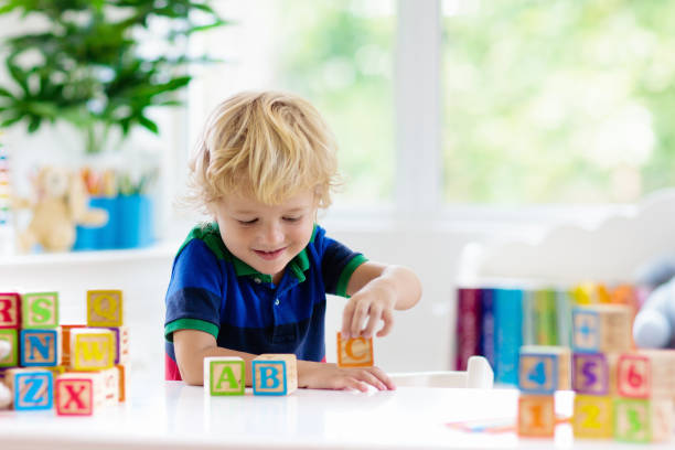 istock Child learning letters. Kid with wooden abc blocks 1148065067