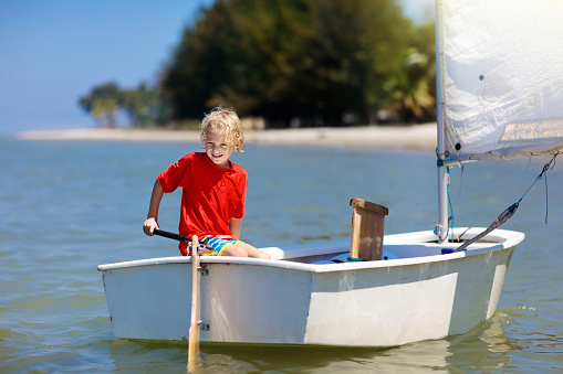 Child sailing. Kid learning to sail on sea yacht. Healthy water sport for school kids. Yachting class for young sailor. Children on boat. Family summer vacation on tropical island. Beach activity.