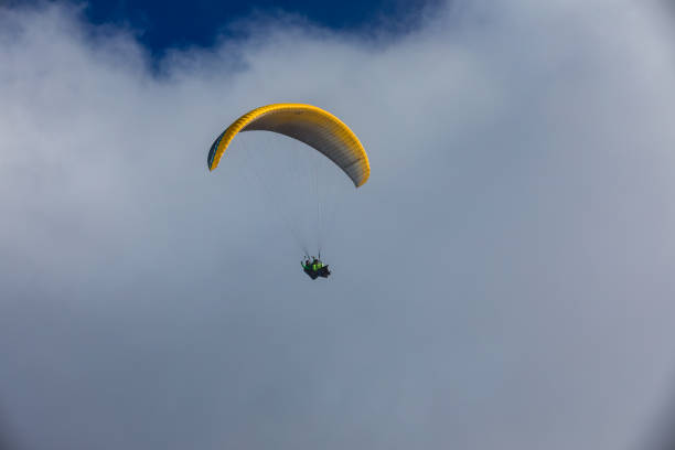 Paragliding at the blue sky . Flying Paraglider extreme sport . Yellow parachute