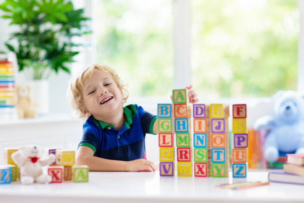 istock Child learning letters. Kid with wooden abc blocks 1148067799