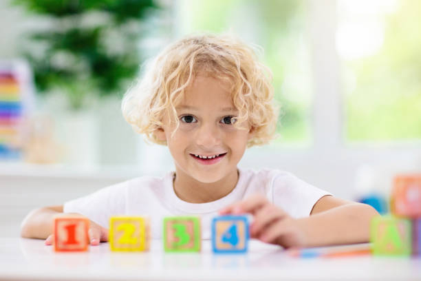 istock Child learning letters. Kid with wooden abc blocks 1148068462
