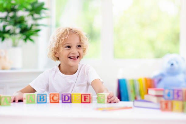 istock Child learning letters. Kid with wooden abc blocks 1148068977