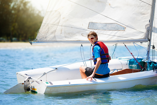 Child sailing. Kid learning to sail on sea yacht. Healthy water sport for school kids. Yachting class for young sailor. Children on boat. Family summer vacation on tropical island. Beach activity.
