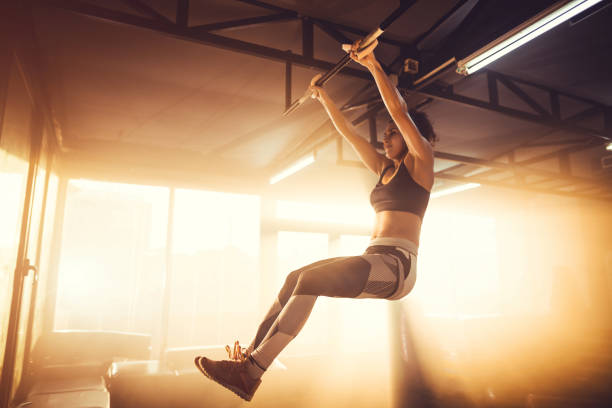 Young adult female doing chin-ups stock photo