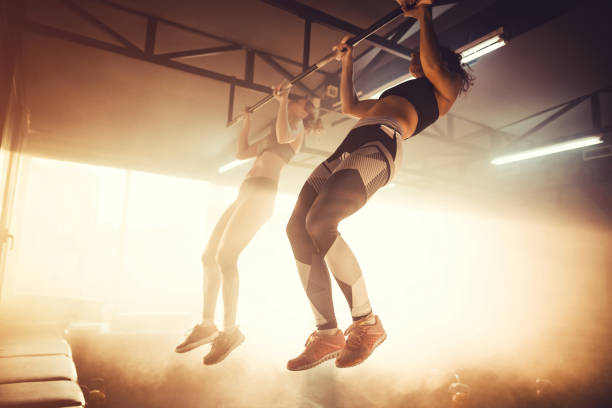 Two women doing pull ups Two women doing pull ups hoisting photos stock pictures, royalty-free photos & images