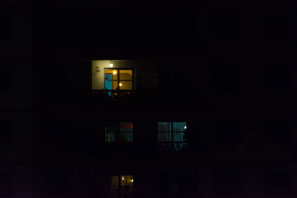 istock Multiple windows of an apartment building at night. Some yellow, some blue, some light on, some light off. 1148085967