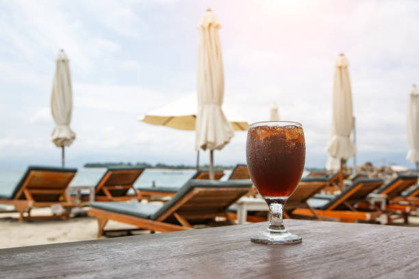 istock Cola glass on beach with umbrellas. Cooling drink 1148090147