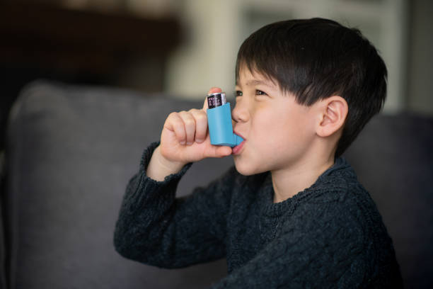 asthmatischer kleiner junge - asthmatic child asthma inhaler inhaling stock-fotos und bilder