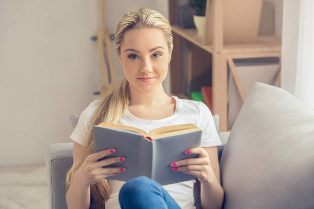 istock Young woman reading book at home leisure 1148093037