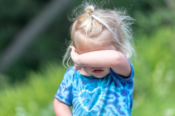 Portrait of sad crying emotional cute little girl looking at camera with face of deep sadness and sorrow outdoors. Sad child with blue eyes, copy space.