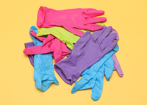 Colorful rubber medical gloves pile on yellow background