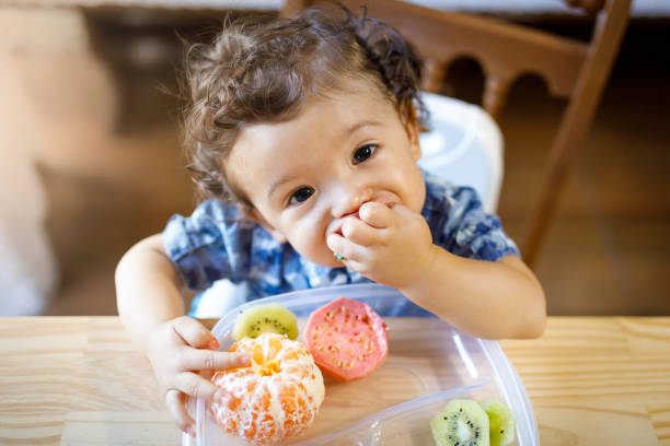 Baby boy eating tasty fruit Baby eating fruits. mini kiwi stock pictures, royalty-free photos & images