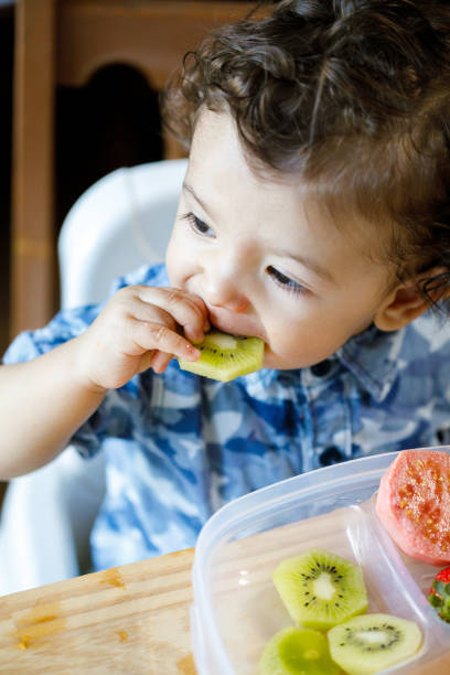 istock Baby boy eating kiwi 1148119021