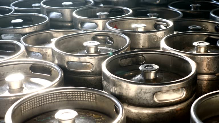 Beer kegs in sunlight stand together in brewery. Steel barrels in a wholesale warehouse ready for shipment. 4k