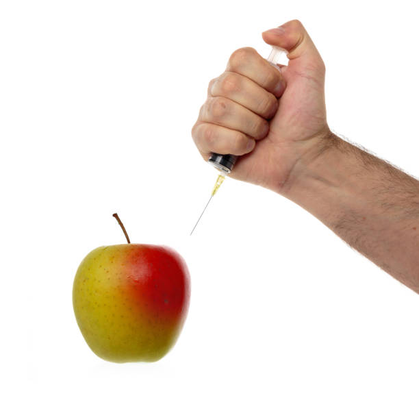 la mano masculina hace una jeringa de inyección en una manzana aislada en blanco. - food crop sprayer insecticide dna fotografías e imágenes de stock