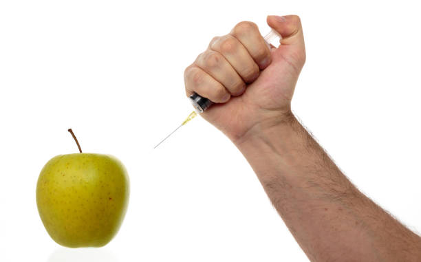 la mano masculina hace una jeringa de inyección en una manzana aislada en blanco. - food crop sprayer insecticide dna fotografías e imágenes de stock