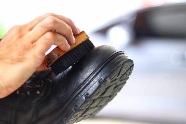 hand of man clean black shoe with blur background