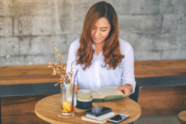 istock a beautiful asian woman holding and reading a book 1148134296