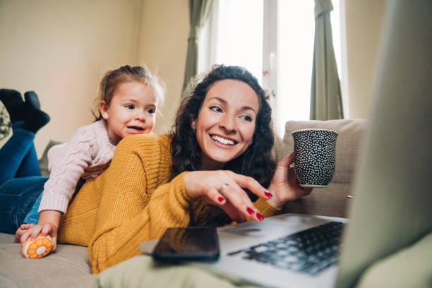 istock Mother and daughter using laptop on sofa 1148143461
