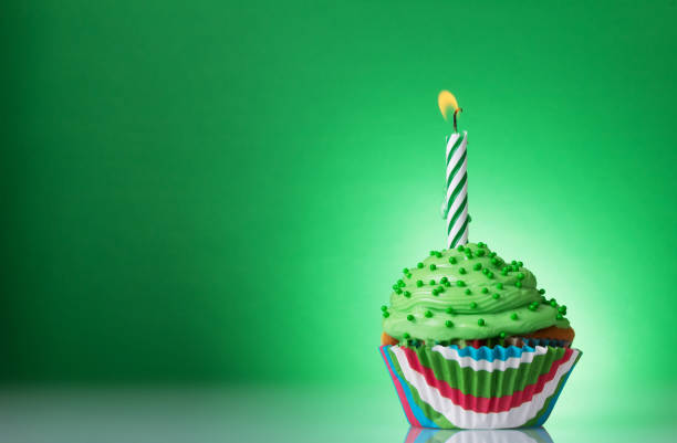 istock Vanilla cupcake with butter cream with a burning candle on a green 1148146797