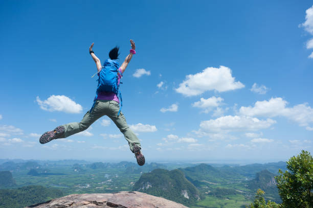istock Happy successful woman hiker jumping on mountain peak cliff edge 1148148236