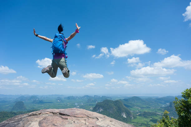 istock Happy successful woman hiker jumping on mountain peak cliff edge 1148148249