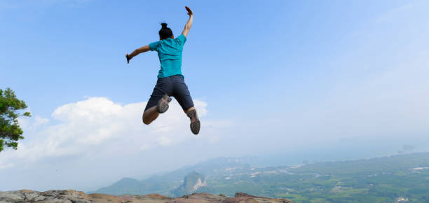 istock successful woman jumping on rocky mountain peak 1148149167