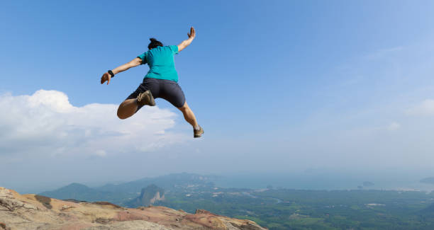 istock successful woman jumping on rocky mountain peak 1148149204