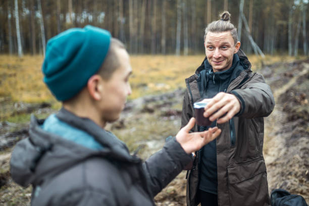 istock Offering Cup of Coffee. Cheerful Men Hikers At Forest Walk 1148154320