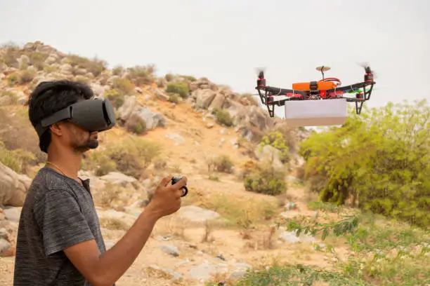 Photo of Young man trying to control drone by controller by seeing at virtual reality viewer