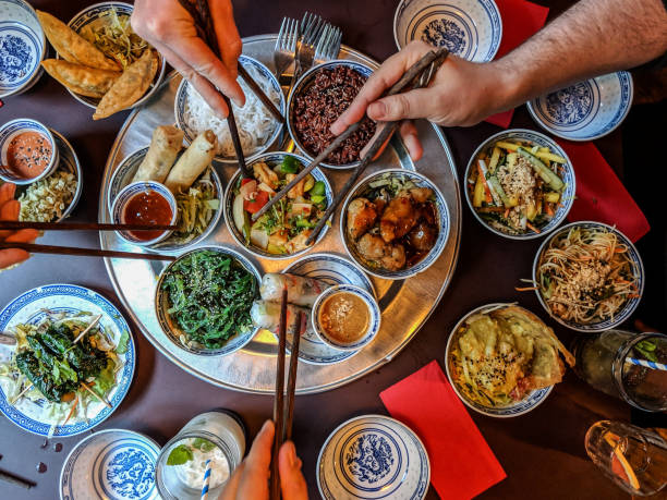 blick aus der vogelperspektive auf menschen, die asiatisches essen essen - asiatische küche stock-fotos und bilder