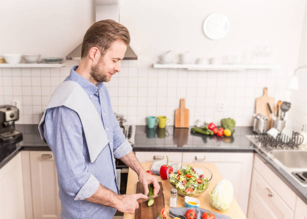 istock Happy smiling man chopping vegetables to make salad 1148161886