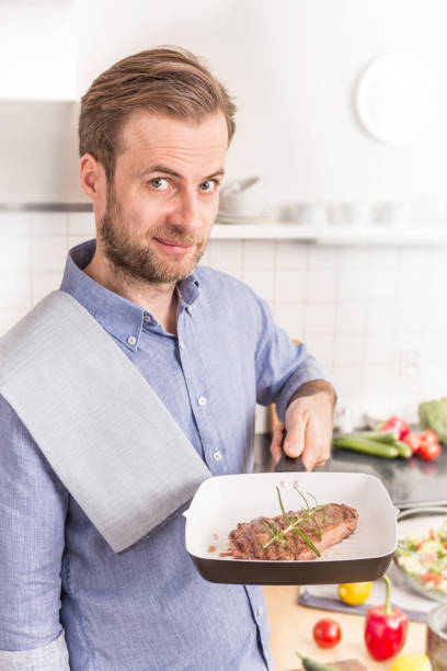 istock Happy man or chef holding pan with grilled steak with rosemary 1148162003