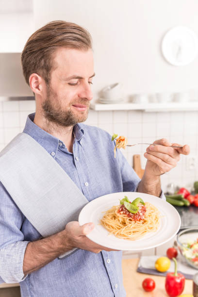 istock Happy smiling man eating spaghetti bolognese in the kitchen 1148162025