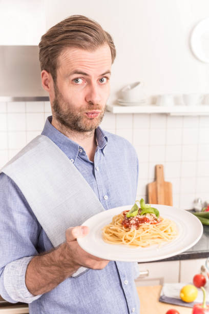 istock Happy smiling man or chef holding plate with spaghetti 1148162026