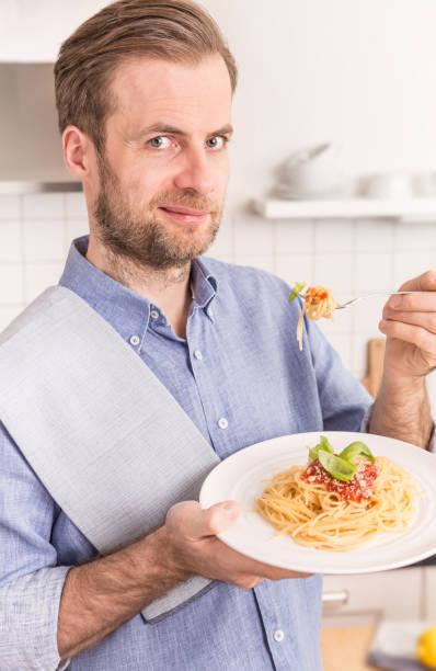 istock Happy smiling man eating spaghetti bolognese in the kitchen 1148162027