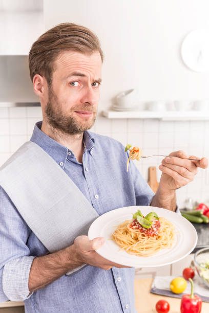 istock Happy smiling man eating spaghetti bolognese in the kitchen 1148162029