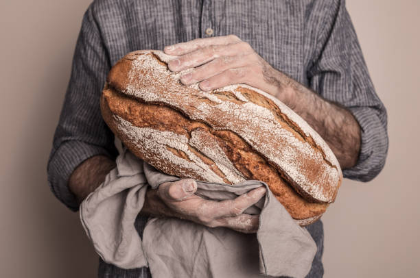 istock Rustic crusty loaf of bread in baker man's hands 1148162903